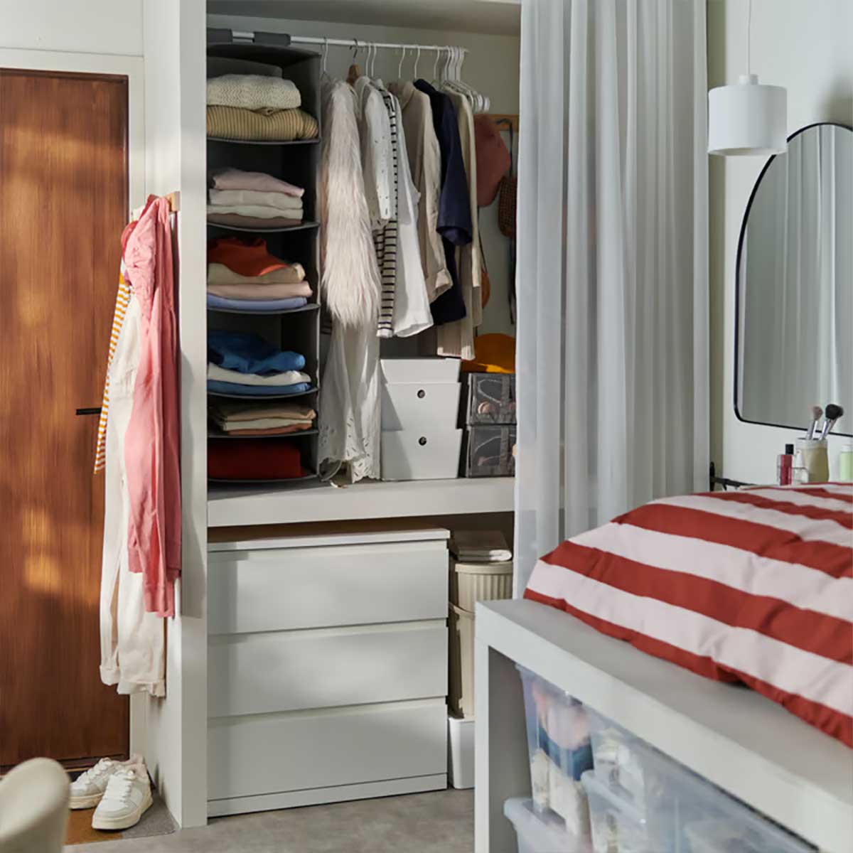 A dorm room with a white STORKLINTA chest of three drawers featuring a neat arrangement of clothing and accessories.