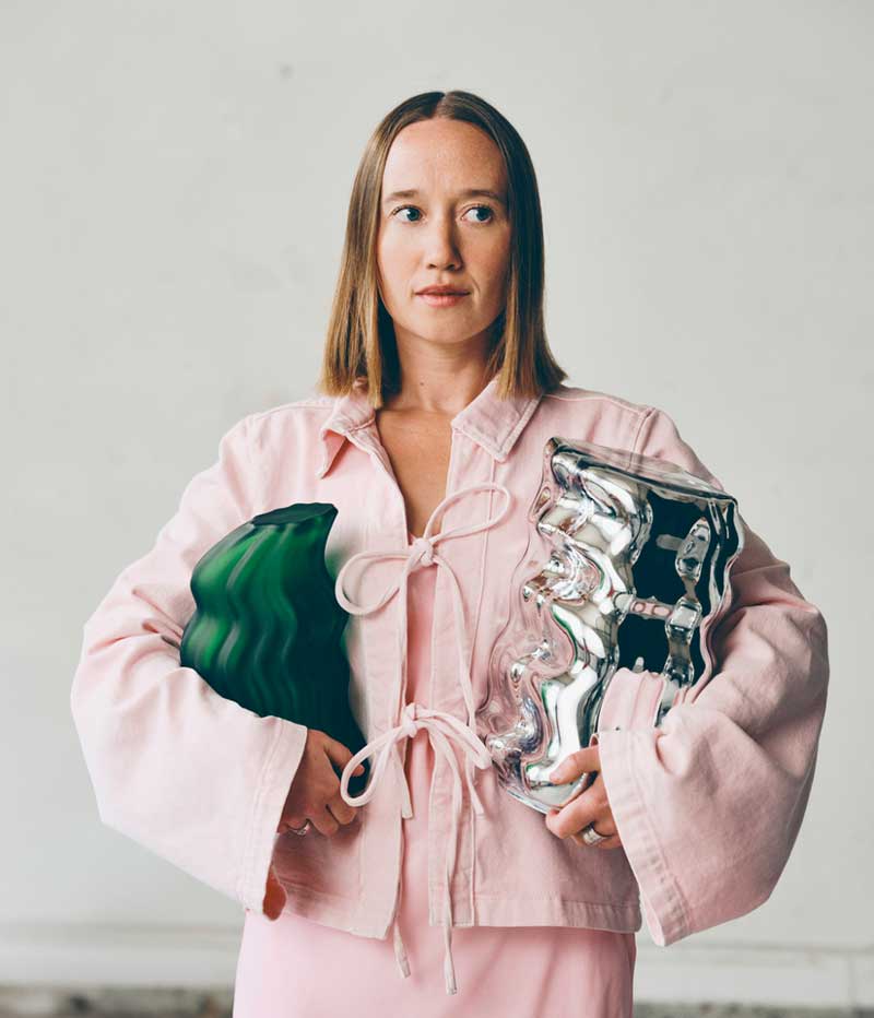 Close up of Lisa Resier in a pink dress holding a green and a metallic sculpture made for IKEA art collection KONSTRUNDA.