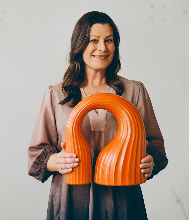 Close up of Lisa Hilland holidig an orange sculpture made for the IKEA KONSTRUNDA art collection.
