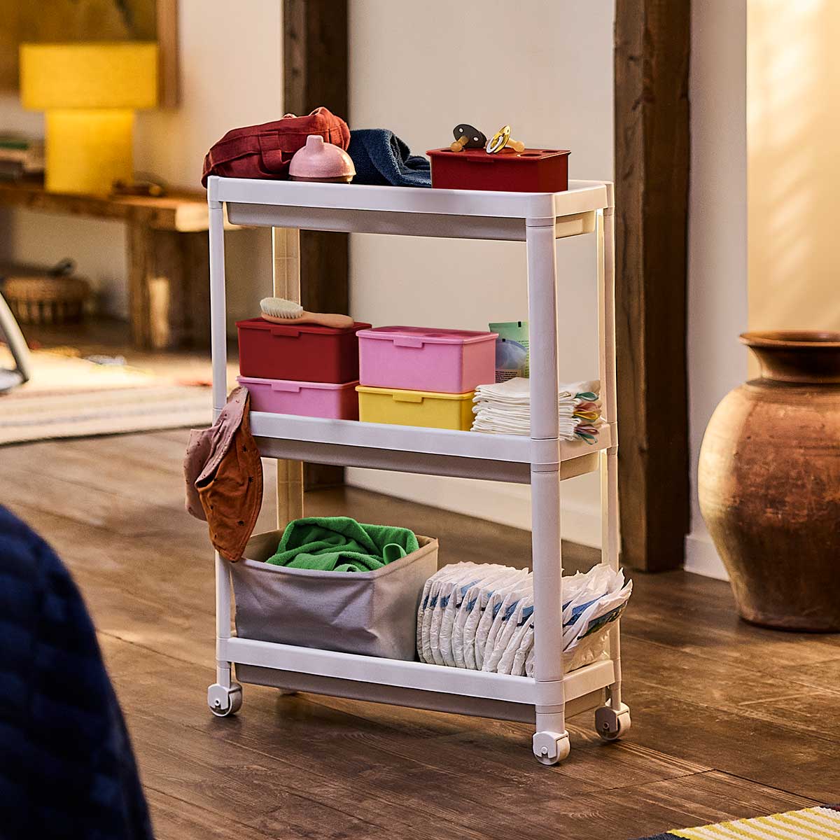 A white VESKEN trolley with wheels stores and organises diapers, washcloths, and other baby items to make nap time easier.
