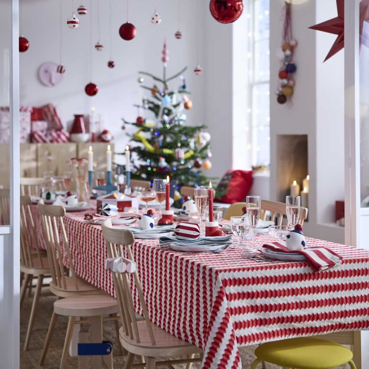 A festive dining table set with tableware, VINTERFINT bird jars with lids, glowing candles and glassware