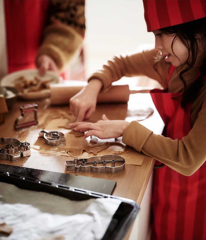 A child cutting out festive cookies from a sheet of dough using VINTERFINT pastry cutters.
