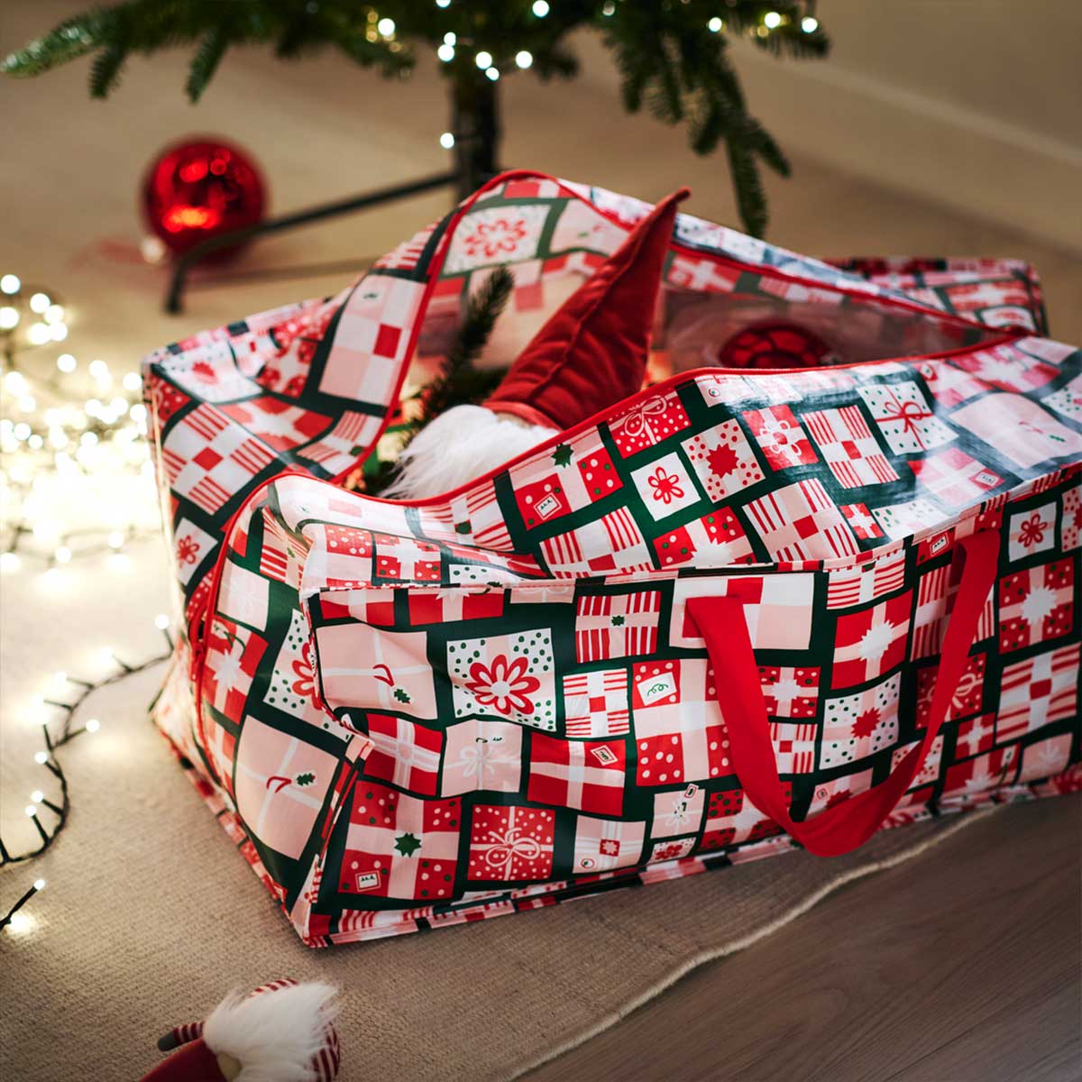 A VINTERFINT storage bag filled Christmas decorations under a VINTERFINT artifical Xmas tree.
