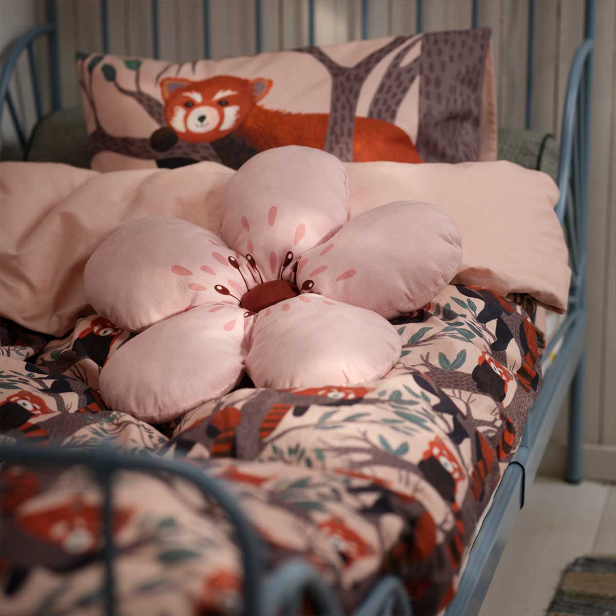 A pink flower ALPTALL cushion on ALPTALL bedding in a child’s bedroom.