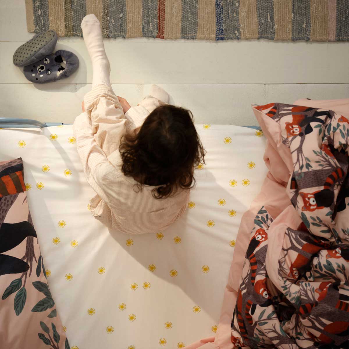 Children pass an ALPTALL wild yak soft toy from the top bunk to the bottom bunk of a bed in a children’s room.